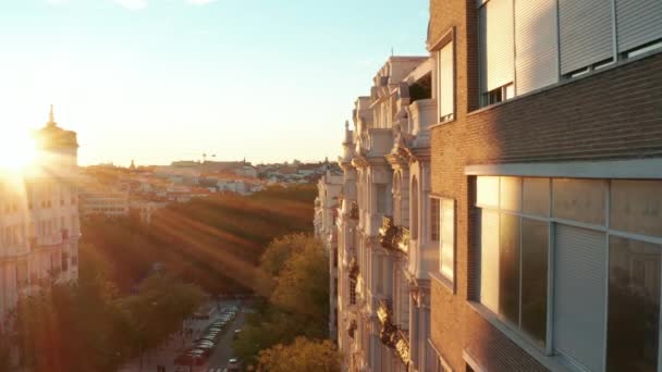Erhöht nach vorne fliegen Häuserzeilen in der Innenstadt entlang. Alter Palast mit dekorierter Fassade, beleuchtet von der untergehenden Sonne. — Stockvideo