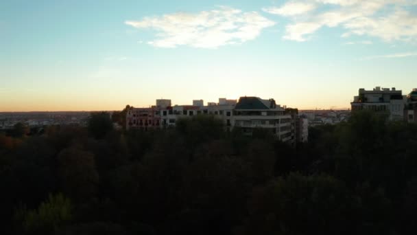 Avante voe acima de árvores no parque e casas de apartamento. Revelando paisagem urbana e pôr do sol no horizonte. — Vídeo de Stock