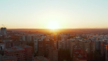 İleri uçaklar şehrin yerleşim bölgesinin üzerinde uçuyor. Konut arazisindeki uzun apartmanlar. Renkli günbatımına karşı görünüm.