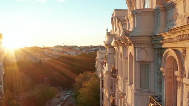Vorne fliegen historische Paläste mit geschmückter Fassade. Erhöhte Ansicht von Gebäuden in der Stadt. Beleuchtet von heller untergehender Sonne. — Stockvideo