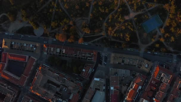 Aerial birds eye overhead top down panning view buildings in urban neighbourhood and public park at sunset. — Stock Video