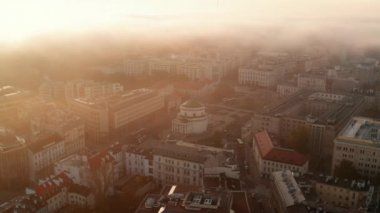Sisli bir sabahta kasabadaki binaların hava manzarası. Parlak altın doğan güneş. Üç Haç Meydanı 'ndaki kilise. Varşova, Polonya