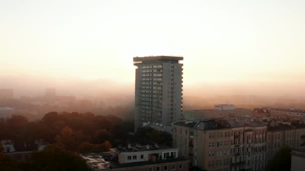 Diapositiva y panorámica de la casa de apartamentos que se eleva por encima de otro desarrollo de la ciudad. Alto prefabricado contra la salida del sol detrás de la niebla. Varsovia, Polonia — Vídeos de Stock