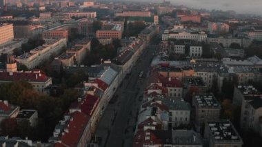 Merkez bölgedeki binaların üzerinden geriye doğru uç. Şehir manzarasını, yükselen güneş tarafından aydınlatılan binalarla yukarı kaldır. Varşova, Polonya
