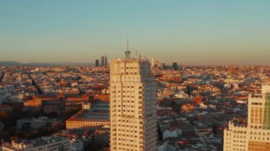Şehir gelişiminin yüksek görüntüsü gün batımı ışığıyla aydınlatılıyor. Torre de Madrid 'in tarihi yüksek binası ön planda.
