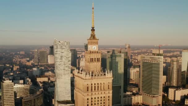 Pull back shot of ornamental top of tall PKIN building. Revealing downtown skyscrapers lit by morning sun. Warsaw, Poland — Stock Video