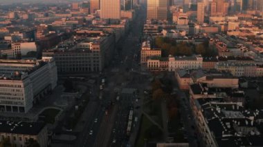 Kavşağın hava görüntülerini kaydır ve tavaya yansıt. Yüksek katlı ofis kulesi arka planda yükselen güneşle aydınlanıyor. Varşova, Polonya