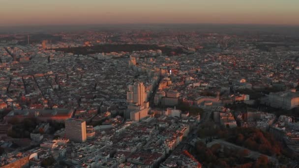 Gökyüzünden şehrin alacakaranlıktaki panoramik görüntüsü. Binalar turuncu günbatımı ışığıyla aydınlatılıyor. — Stok video