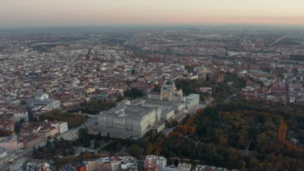 Descending footage of Royal Palace and Almudena Cathedral at dusk. Aerial panoramic footage of city with historic landmarks. — Stock Video