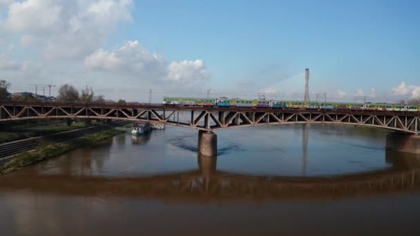 Vistula Nehri üzerindeki eski çelik demiryolu köprüsünden uç. Grafiti ressamı banliyö trenini rayına oturttu. Modern yol kablolarının köprü olarak kalması. Varşova, Polonya — Stok video