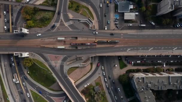 Nehir kıyısındaki yol kavşağındaki hava kuşları tepeden aşağıya doğru bakıyor. Tramvaylar tren durağında duruyor. Şehirde bir nakliye aracı. Varşova, Polonya — Stok video