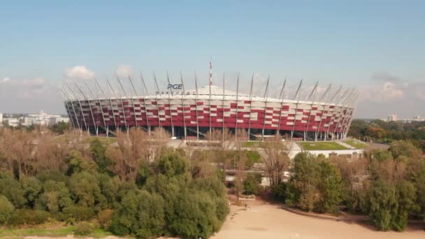 Vola intorno allo stadio nazionale polacco, moderna arena multifunzione. Vista ad angolo basso sopra gli alberi nel parco. Varsavia, Polonia — Video Stock