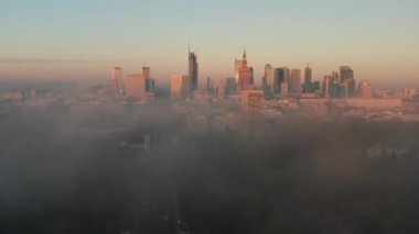 İlerisi sislerin üstünde uçar. Şehir merkezindeki yüksek binaların güneş ışığında panoramik görüntüleri. Şehir manzarası ortaya çıkıyor. Varşova, Polonya