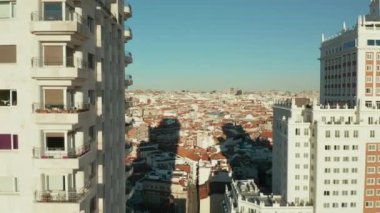 Pencereleri ve balkonları olan duvar boyunca yükselen hava görüntüleri. Arkaplanda Torre de Madrid tarihi gökdelen ve şehir manzarası.