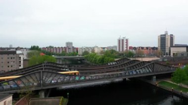 Şehirdeki nehir üzerinden çelik köprünün üzerinden uçmak. Banliyö treni çok raylı demiryolu hattında çalışıyor. Arka planda ikamet eden bir mahalle. Berlin, Almanya