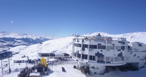 Húzza vissza a felvétel felső kábel autó állomás és étterem. Felfedi a téli hegyi tájat. napos nap tiszta égbolttal. Laax, Svájc — Stock videók