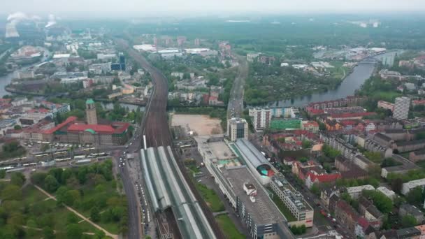 Şehrin havadan panoramik görüntüsü. Tren istasyonunun çevresindeki yerleşim yerlerinde trafik vardı. Arka planda sigara fabrikası bacaları olan sanayi bölgesi. Berlin, Almanya — Stok video