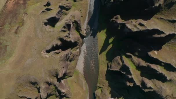 Blick über den Fluss Fjadra, der durch den Canyon Fjadrargljufur fließt. Blick von oben auf den 100 Meter tiefen Canyon im Süden Islands mit einem Fluss, der durch moosgrüne, bewachsene Hügel fließt — Stockvideo