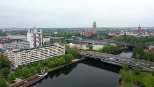 Zdjęcia lotnicze ruchliwej drogi wielopasmowej na moście nad budynkami wodnymi i apartamentowymi nad brzegiem rzeki Havel. Wieża ratusza w tle. Berlin, Niemcy — Wideo stockowe