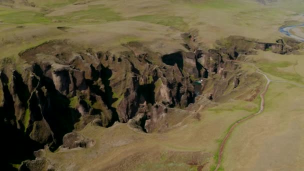 Vista panorâmica de cima para baixo do desfiladeiro Fjadrargljufur, um desfiladeiro de 100 metros de profundidade no sul da Islândia. Vista drone da majestosa formação rochosa causada pela erosão do rio Fjadra que flui através dele — Vídeo de Stock
