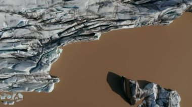 Çamur Vatnajokull Gölü Ulusal Parkı 'nda Breidamerkurjokull buzulunun buzul oluşumunun yukarıdan görünüşü çatladı. Çevresel koruma. Yukarıdan aşağıya buzul desenli buz ve göl manzarası