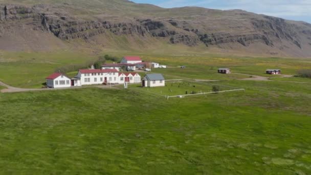 Drone vista de la pequeña iglesia y cementerio en un asentamiento rural en el campo de Islandia. Vista aérea de un pequeño pueblo en las tierras altas de Islandia — Vídeo de stock