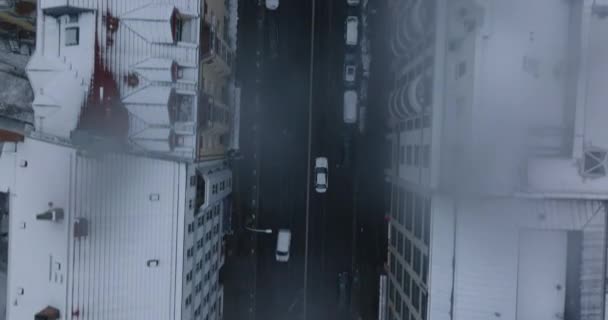Aerea occhio uccelli sopra la testa verso il basso panoramica vista sulla guida in auto su strada in città d'inverno. Tetti innevati di edifici intorno. Berlino, Germania — Video Stock