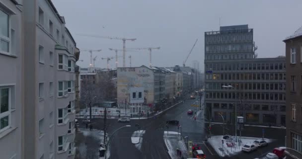 Bajo tráfico en la intersección de carreteras en la ciudad de invierno. Grupo de grúas torre en obra en segundo plano. Berlín, Alemania — Vídeos de Stock