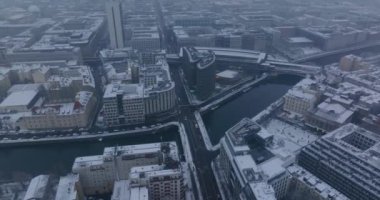 Şehir merkezindeki karlı binaların hava panoramik görüntüleri. Nehir sakin bir şekilde kış kasabasından akıyor. Berlin, Almanya