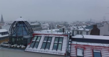 Çatı pencereleri ve şehrin köşesindeki lüks çatı katı dairesinin cam kubbesinin etrafında uçmak. Kar yağışlı kış havası. Berlin, Almanya