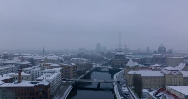 Şehir merkezindeki Spree nehrinin üzerinden geriye doğru uç. Köprüde suyla giden arabalar. Rıhtımdaki binalar karla kaplıydı. Berlin, Almanya — Stok video