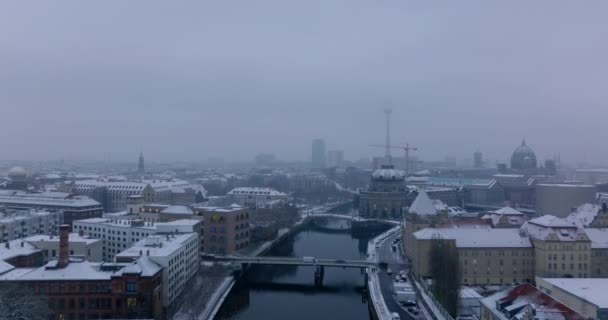 Flyg bakåt ovanför floden Spree i centrum. Bilar kör på bron över vatten. Snödammade byggnader vid vattnet. Berlin, Tyskland — Stockvideo