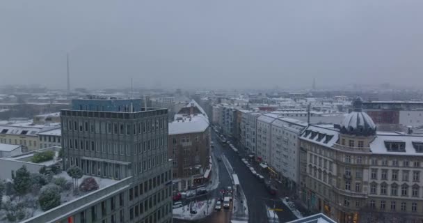 Riprese aeree di tetti innevati nel distretto cittadino. Avanti volare sopra le auto che guidano su strada in città. Berlino, Germania — Video Stock