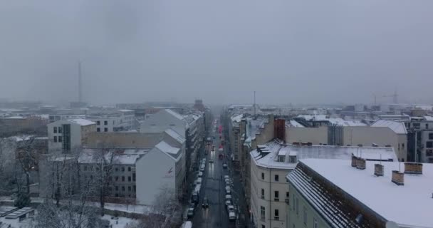Adelante vuelan por encima de la ciudad de invierno. Nieva en el barrio urbano. Calle bordeada por casas de apartamentos de varios pisos. Berlín, Alemania — Vídeo de stock