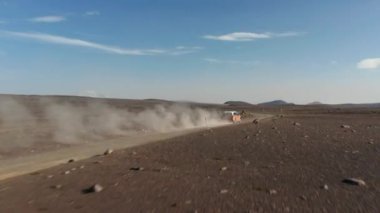 İzlanda 'da çöl yolunda seyir halindeki aracın insansız hava aracı görüntüsü. İnanılmaz bir hava manzarası, İzlanda manzarası, araba tozlu yolda dağları keşfediyor. Ticari sigorta.