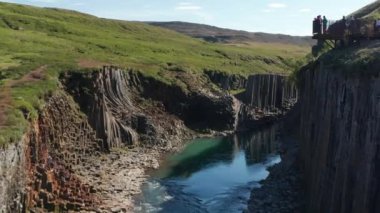 Studlagil Kanyonu 'nun iki lav duvarı arasında bazalt sütunlar ve buzullu su nehri manzarası. Bazalt kaya oluşumları ve Jokulsa nehri ile ünlü bir turistik alan.