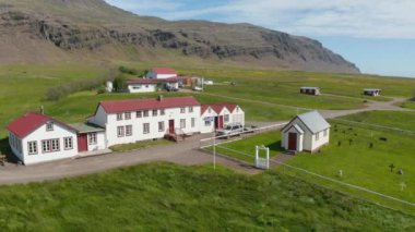 İzlanda 'nın kırsal kesimindeki küçük kilise ve mezarlığı olan tipik bir binanın etrafındaki hava manzarası. Kuşların gözü küçük yerleşim yerlerinde dalgalanan rüzgarda dalgalanan bayraklarla