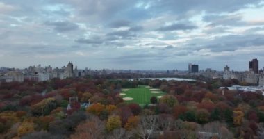 İleri, Central Park 'ın üzerinden uçuyor. Beyzbol sahası ve Jacqueline Kennedy Onassis Reservoir ile Büyük Bahçe Sonbahar renk ağaçlarıyla çevrili. Manhattan, New York City, ABD