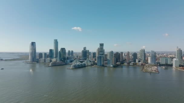 Vpřed letí nad vodu. Panoramatický záběr budov v centru na břehu řeky. Moderní vysoké mrakodrapy. Jersey City, USA — Stock video