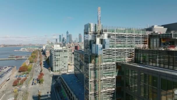 Voe em torno do canteiro de obras em um novo prédio à beira-mar. Elevador de construção a subir. Revelando o horizonte com arranha-céus modernos. Manhattan, Nova Iorque, EUA — Vídeo de Stock