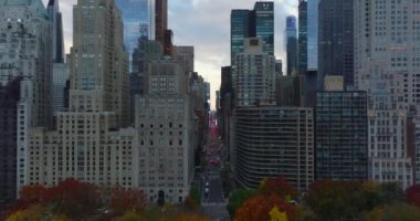 Central Park 'ı çevreleyen yüksek binalar arasında ileriye doğru uçar. Geniş caddenin üzerinden uç, kırmızı fren lambaları. Manhattan, New York City, ABD