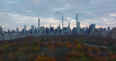Central Park 'ı çevreleyen gökdelenlerin geniş panoramik manzarası. Geriye doğru, sonbahar ağaçları arasındaki turistik cazibeyi ortaya çıkarıyor. Manhattan, New York City, ABD