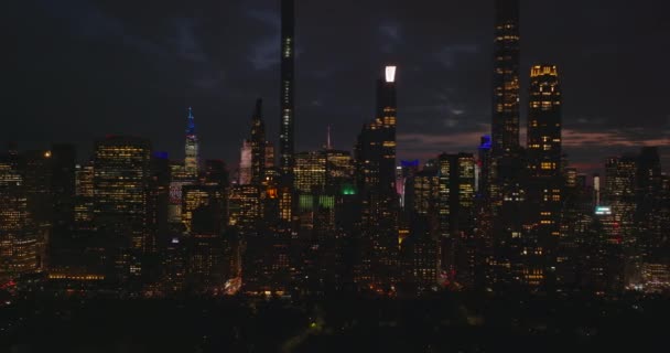 Deslizando revelar do panorama da cidade noturna. Edifícios altos iluminados do centro da cidade e avenidas largas. Efeito paralaxe. Manhattan, Nova Iorque, EUA — Vídeo de Stock
