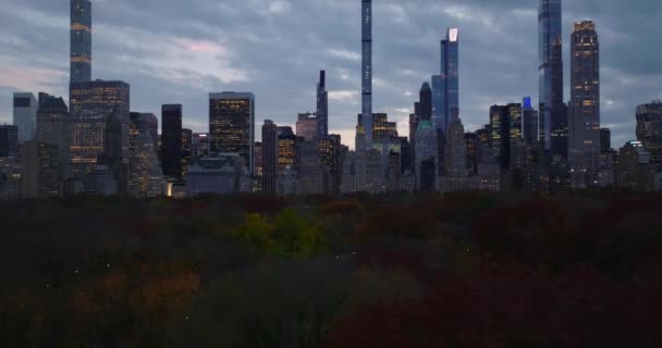 Slide och panorera bilder av centrum skyskrapor och höghus kontor mot skymningen himlen. Lågt flyg ovanför höstens Central Park. Manhattan, New York City, USA — Stockvideo