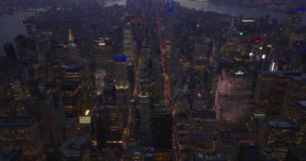 High angle view of long straight avenues passing city district between high rise buildings. Tilt up reveal of city panorama at dusk. Manhattan, New York City, USA — Stock Video