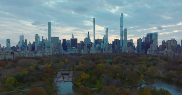 Forwards fly above lake and Bethesda Terrace in autumn Central park. Downtown skyscrapers panorama. Manhattan, New York City, USA — 图库视频影像