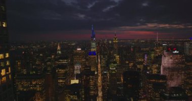 Gece şehrinin üzerinde geriye doğru uç. Şehir merkezindeki gökdelenleri renkli alacakaranlık gökyüzüne karşı aydınlattı. Manhattan, New York City, ABD