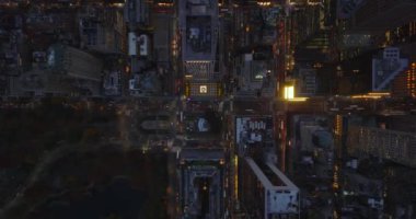 Gökyüzü kuşları şehir merkezindeki akşam manzarasını yukarıdan izliyorlar. Aydınlanmış sokaklar ve yüksek katlı ofis binaları. Manhattan, New York City, ABD