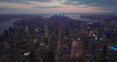 Alacakaranlık vakti suyla çevrili büyük şehrin panoramik hava manzarası. Yüksek binalar ve caddelerdeki trafik. Manhattan, New York City, ABD