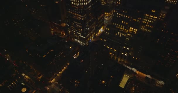 Wysoki kąt widzenia ulic w nocnym mieście. Przechył w górę ujawnić wysoki budynek z oświetlonymi oknami w śródmieściu. Manhattan, Nowy Jork, USA — Wideo stockowe